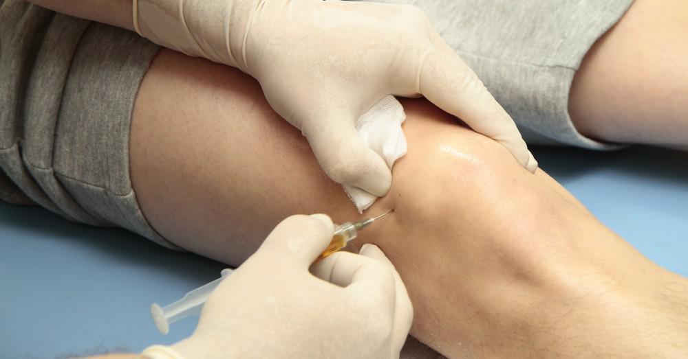 Doctor giving patient an injection in his knee