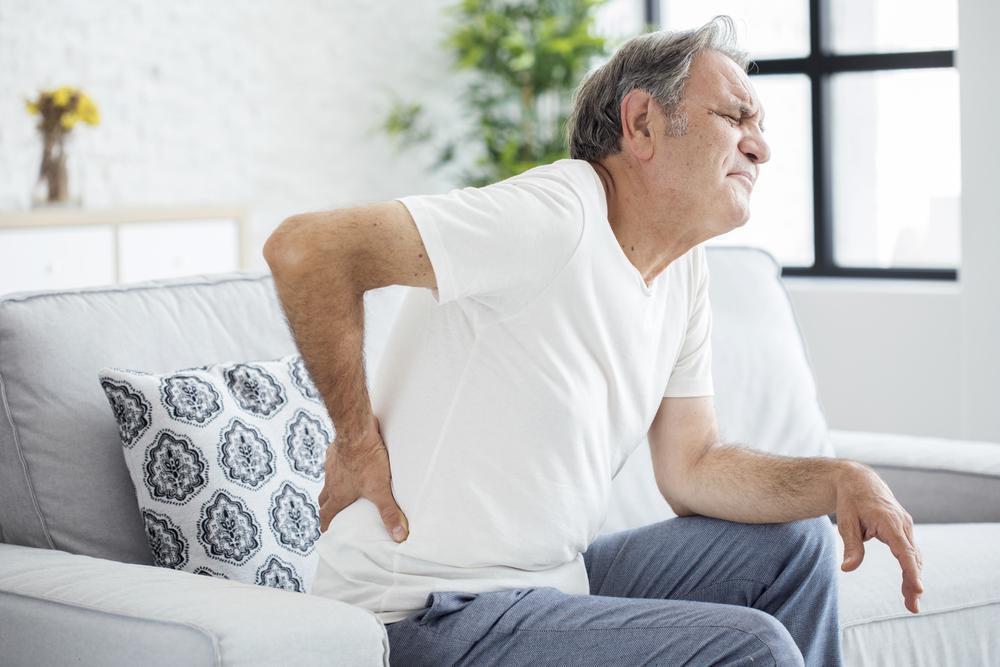 Older gentleman sitting in chair showing back pain