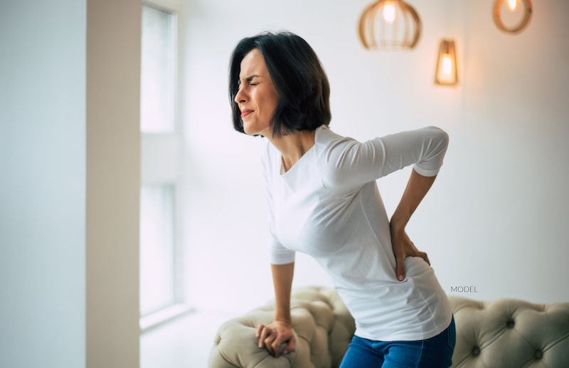 Middle-aged woman holding her lower back in pain